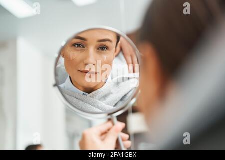 Femme sérieuse concentrée regardant elle-même dans le miroir Banque D'Images