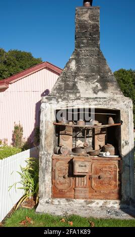 Ancien poêle en fonte dans les restes de cheminée de maison à l'extérieur. Banque D'Images