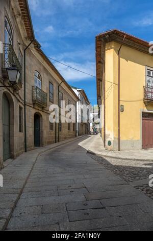 Guimaraes / Portugal - 12 09 2020 : vue sur une rue ancienne et étroite avec des bâtiments classiques dans le centre ville de Guimaraes, couple marchant sur fond Banque D'Images