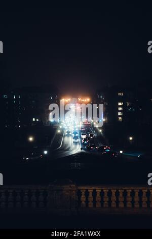 Avenue droite pendant une nuit de pluie à Munich, Bavière, Allemagne. Le pont mène sur l'Isar (rivière de Munich). Les feux de circulation illuminent la scène sombre Banque D'Images