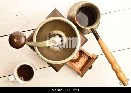 Moulin à café manuel en bois avec une tasse de café et une cale, gros plan, sur une table en bois, vue de dessus. Banque D'Images