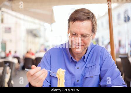 Beau caucasien mangeant des spaghetti au restaurant extérieur italien Banque D'Images