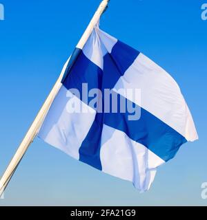 Drapeau national de la Finlande flottant sur le vent contre un ciel bleu clair. Banque D'Images