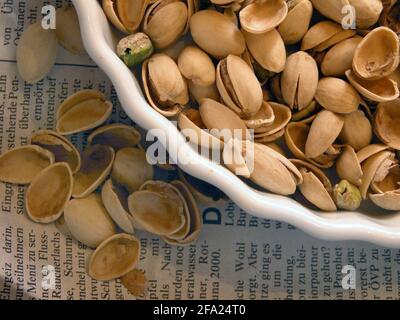 Pistaches (Pistacia vera), pistaches dans un bol, noix sur un journal, Autriche Banque D'Images