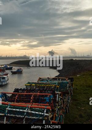 Une vue sur Paddy’s Hole, South Gare, emportant les petits bateaux de la flotte de pêche et les méga-structures des ports de conteneurs à l’horizon. Banque D'Images