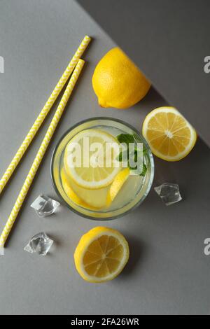 Verre de limonade et ingrédients sur fond gris clair Banque D'Images