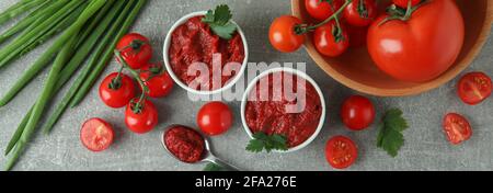 Bols avec pâte de tomate sur fond gris avec ingrédients Banque D'Images