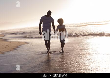 Père et fille afro-américains marchant et tenant la main la plage Banque D'Images