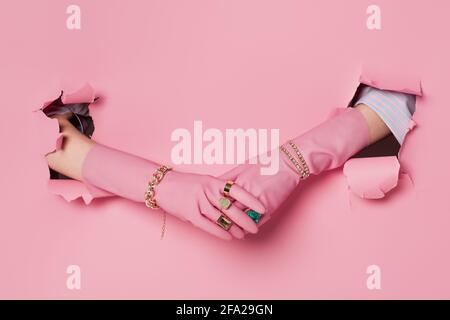 Vue rognée de la femme dans des bagues, des bracelets et des gants près de fond rose avec trous Banque D'Images