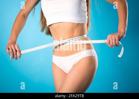 Régime alimentaire et perdre du poids - jeune femme est la mesure de sa taille avec un ruban à mesurer Banque D'Images