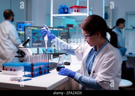 Un ingénieur scientifique médical utilise une micropipette, une pipette pour prélever l'échantillon dans un tube à essai. Femme recherche une nouvelle expérience dans un laboratoire moderne, en analysant le travail pharmaceutique avec des équipements modernes. Banque D'Images