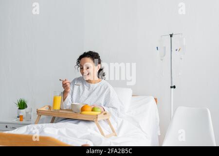 bonne femme afro-américaine prenant le petit déjeuner près de fruits frais et jus d'orange à l'hôpital Banque D'Images