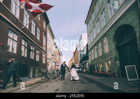 Copenhague, Danemark 11 juin 2019. Couple de mariage marchant dans la rue sur le fond du drapeau du Danemark. Banque D'Images