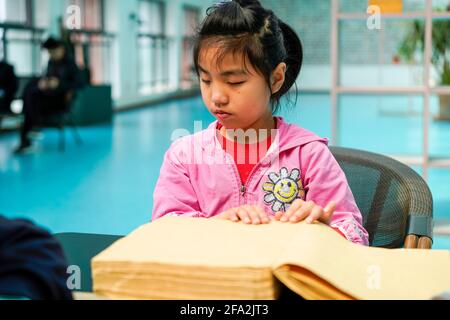 (210422) -- CHONGQING, le 22 avril 2021 (Xinhua) -- UNE étudiante malvoyante lit avec ses mains à la bibliothèque du centre d'éducation spéciale de Chongqing, dans la municipalité de Chongqing, dans le sud-ouest de la Chine, le 22 avril 2021. En prévision de la Journée mondiale du livre qui aura lieu le 23 avril, le Centre d'éducation spéciale de Chongqing a lancé une série d'activités telles que l'ouverture de cours de livres audio, l'organisation de coins de lecture et l'offre de livres en braille pour enfants malvoyants. (Canal Xinhua/Liu) Banque D'Images