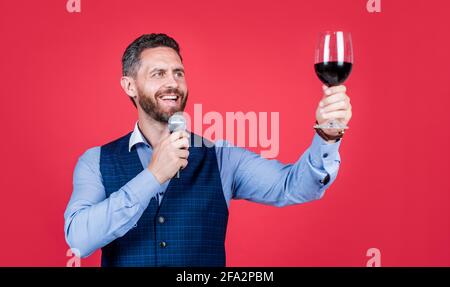 Happy man toastmaster lève un verre de vin pour proposer des toasts avant de boire un fond rouge, des encouragements Banque D'Images