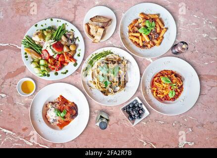 Quelques assiettes de délicieux plats italiens sur marbre rose texturé Banque D'Images