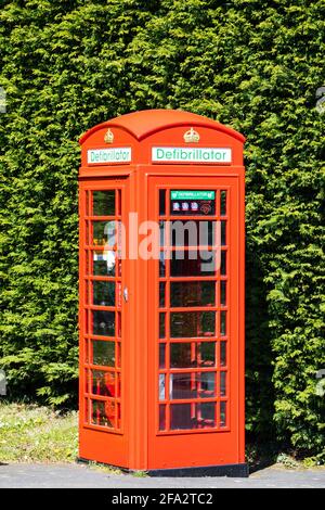 Coffret téléphonique britannique rouge traditionnel, maintenant utilisé pour accueillir un défibrillateur dans le village de Denton. Lioncolnshire, Angleterre Banque D'Images