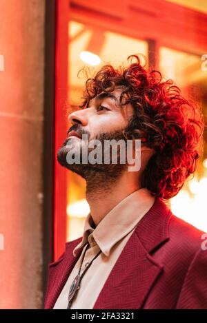 portrait latéral vertical d'un jeune homme caucasien recevant la lumière de néon d'une barre sur ses cheveux. Il s'habille de vêtements tendance Banque D'Images