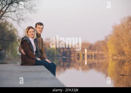 Cute couple sitting at Riverside sur coucher de soleil en automne chaud soir date romantique. Banque D'Images
