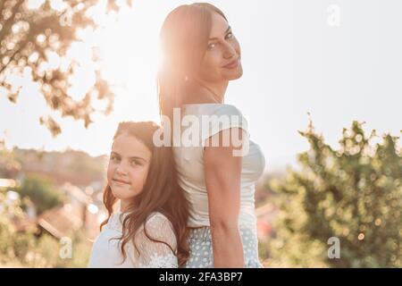 Mère et fille debout dos à dos. Lumière de l'après-midi Banque D'Images