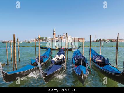 Venise, province de Venise, région de Vénétie, Italie. Gondoles amarrées dans le Bacino di San Marco. San Giorgio Maggiore derrière. Venise et sa lagune sont un Banque D'Images