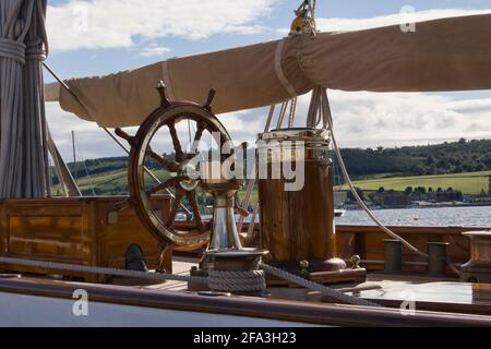 Pont d'un yacht construit par Fyfe à Rhu Marina, Argyll, Écosse avec gréement, roue et boussole. Banque D'Images