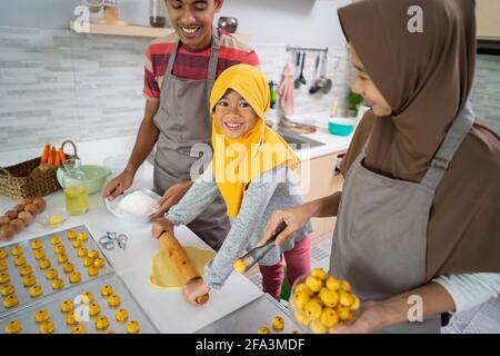 famille musulmane heureuse avec hijab faisant le gâteau nasar ensemble Banque D'Images