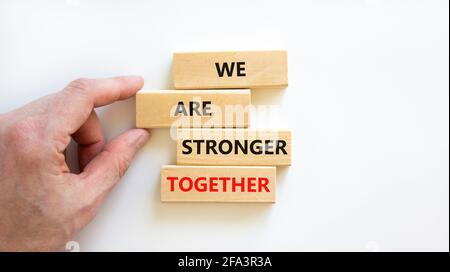 Symbole « plus fort ensemble ». Bloc en bois avec les mots « nous sommes plus forts ensemble ». Magnifique fond blanc. Main d'homme d'affaires. Copier l'espace. Affaires, moti Banque D'Images