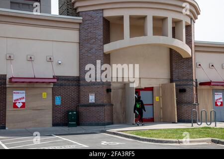 Minneapolis, Minnesota. Une femme entre dans une pharmacie CVS est montée pour la protection pendant l'essai Derek Chauvin en cas d'émeute. Banque D'Images