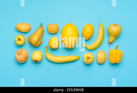 Plat Lay avec divers fruits et légumes jaunes sur une table bleue. Légumes et fruits frais disposés symétriquement sur un fond coloré Banque D'Images