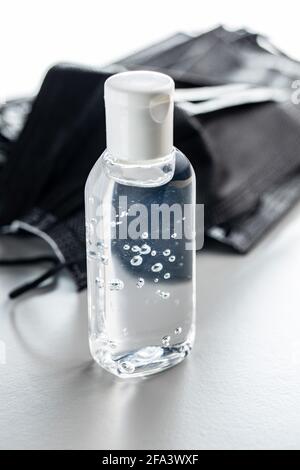 Gel désinfectant pour les mains anti-coronavirus en flacon. Gel désinfectant pour les mains et masque chirurgical sur fond gris. Banque D'Images