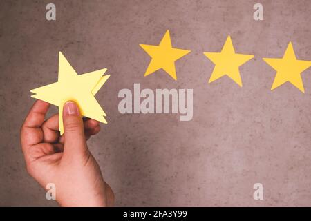Concept d'expérience client. Trois étoiles jaunes sur fond de béton. Feedback négatif - sélection manuelle d'un 3 étoiles Banque D'Images