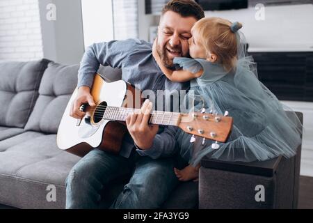 Père joue la guitare pour sa petite fille. Banque D'Images