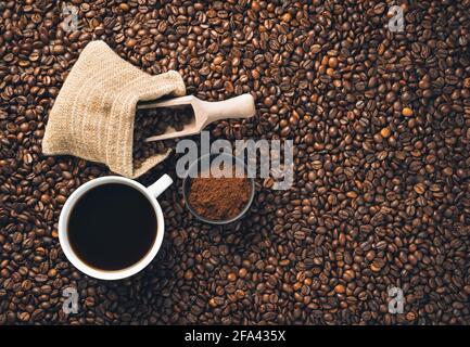 Du café moulu, des grains de café et une tasse de café sur des grains de café épars. Vue de dessus, horizontale. Banque D'Images