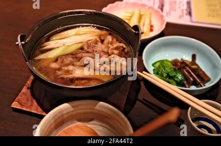 Accent sélectif sur un bol d'imoni, un ragoût traditionnel de bœuf et de pommes de terre de la région de Yamagata au Japon, ainsi que quelques plats d'accompagnement Banque D'Images