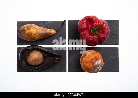 Groupe de différents fruits et légumes en rotation et avec moule sur elles placées sur des plaques noires Banque D'Images