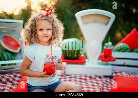 Enfant buvant de la limonade à la pastèque dans un pot avec de la glace et de la menthe comme s Banque D'Images