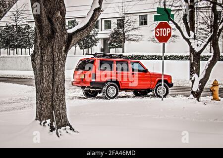 Le 4x4 s'est arrêté au panneau d'arrêt le jour de la neige pour se préparer à tourner sur le déneigement roat de la route dans un quartier haut de gamme. Banque D'Images