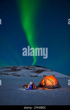 Le scientifique est assis à l'extérieur de sa tente avec Northern Lights dedans le ciel Banque D'Images