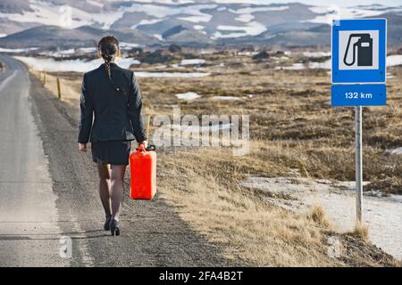 Femme d'affaires marchant avec le gaz peut sur la route vide dedans Islande Banque D'Images