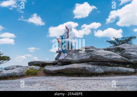 Femme assise en haut de la montagne portant un masque de visage regardant autour Banque D'Images