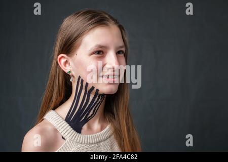 Fille avec bande noire de kinésiologie rayée placée sur le cou Banque D'Images