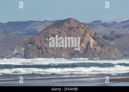 Les vagues de l'océan Pacifique mettent en valeur le Morro Rock historique, une ancienne prise volcanique qui se dresse à l'embouchure de la baie Morro en Californie. Banque D'Images