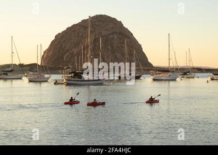 Des kayakistes de loisirs pagaient à travers le célèbre port de Morro Bay en Californie avec Morro Rock formant le fond mémorable sur la côte de Cenral. Banque D'Images