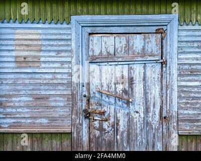 porte fermée avec cadenas sur une grange en bois aux intempéries peinte en bleu mur Banque D'Images