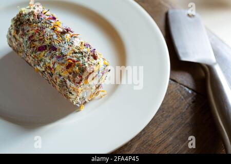 Une assiette de fromage de chèvre frais avec du miel et des fleurs et un couteau à fromage sur la table en bois sombre Banque D'Images