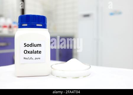 Mise au point sélective d'un flacon de produit chimique toxique à base d'oxalate de sodium pur à côté d'une boîte de Petri avec une poudre de cristal solide blanche. Laboratoire blanc Banque D'Images