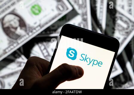 Dans cette illustration, le logiciel d'application de télécommunication pour les chats vidéo et les appels vocaux logo Skype vu sur un écran d'appareil mobile Android avec la devise de l'icône dollar des États-Unis, symbole d'icône $ en arrière-plan. Banque D'Images