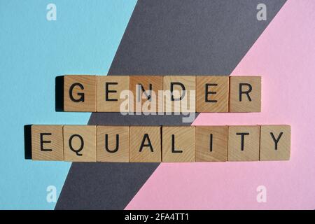 Égalité des sexes, mots en lettres de l'alphabet en bois, isolés sur fond rose, bleu et gris Banque D'Images