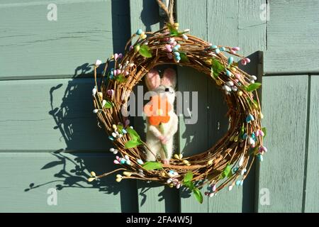 Couronne de Pâques avec un lapin, accrochée sur un mur vert Banque D'Images